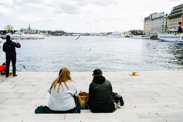 People relaxing on embankment near Gamla Stan, Stockholm old town. Lake Malaren