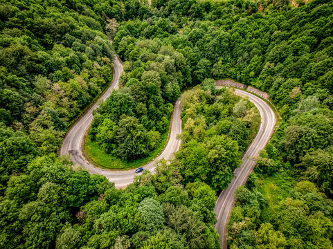 Extreme winding highway in the mountains passing trough a forest. Aerial view.