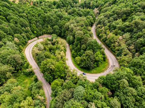 Extreme winding highway in the mountains passing trough a forest. Aerial view.