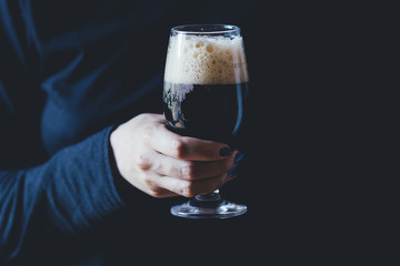Woman holds a glass of dark beer