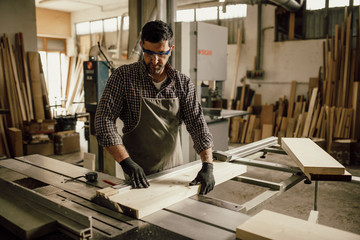 Skilled carpenter cutting a piece of wood in his woodwork workshop