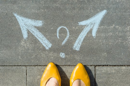 Female legs with 2 arrows and question mark, painted on the asphalt