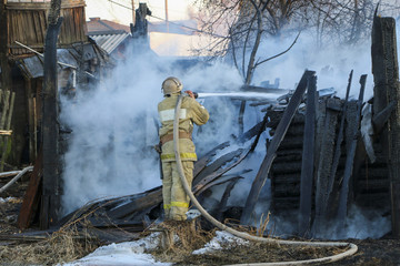 Firefighter extinguishes the fire. Fireman holding a hose with water, watering a strong stream of...