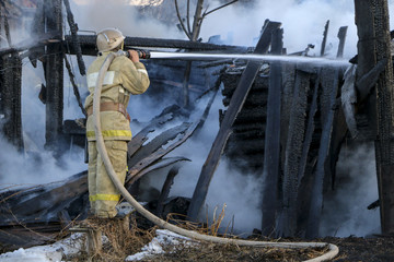 Firefighter extinguishes the fire. Fireman holding a hose with water, watering a strong stream of...