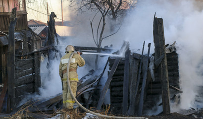 Firefighter extinguishes the fire. Fireman holding a hose with water, watering a strong stream of...