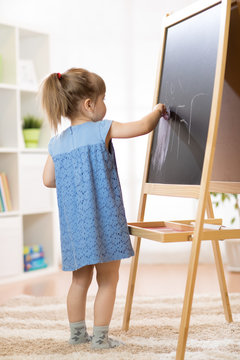 Child Girl Painting At Easel In School.