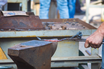 blacksmith performs the forging of hot glowing metal on the anvil