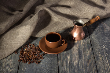 Naklejka premium Coffee pot, Cup and saucer, coffee beans on wooden surface