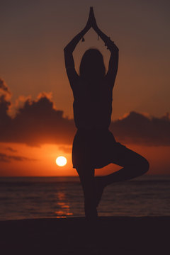 Young woman practicing yoga on the beach. © Kitja