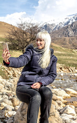 Beautiful blonde with flying hair in the wind on the bank of a mountain river