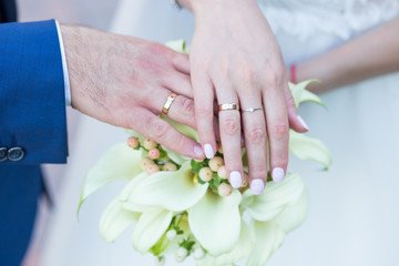 gold rings on the fingers of the newlyweds and a wedding bouquet