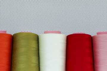 Sewing threads on spool in the white metal grid.