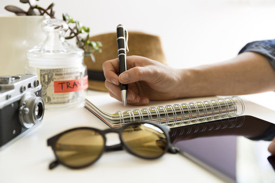 Travel planning concept on table.  Traveler's accessories and items with notebook and money saving jar, sunglasses and hat