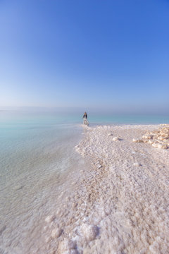 Blonde young woman in a long skirt on the shore of the dead sea. Jordan