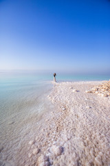 Fototapeta na wymiar Blonde young woman in a long skirt on the shore of the dead sea. Jordan