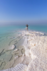 Blonde young woman in a long skirt on the shore of the dead sea. Jordan