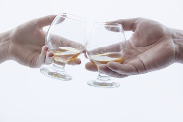 two hands, two glasses of alcohol .