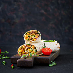 Burritos wraps with beef and vegetables on  black background. Beef burrito, mexican food. - obrazy, fototapety, plakaty