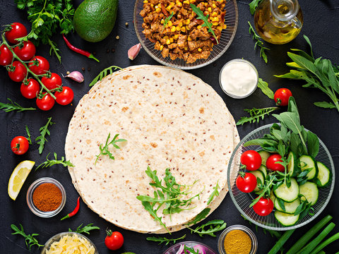 Ingredients for burritos wraps with beef and vegetables on black background. Mexican food. Top view. Flat lay