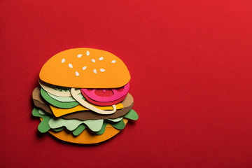 Creative art conceptual collage with space for text. Stylized craft paper burger a red background. Composition cut out from colored paper. Illustrative picture.