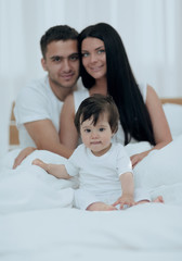 Fototapeta na wymiar Portrait of a joyful family sitting on the bed at home