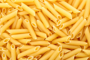 Uncooked penne pasta as background, closeup