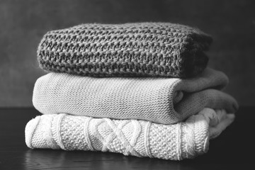 Stack of warm knitted clothes on table