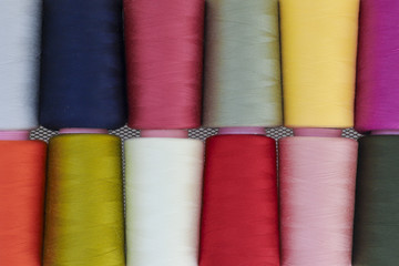 Sewing threads on spool in the white metal grid.