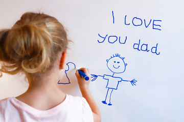Little girl draws  family with marker on a white board.