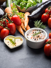 Mix of raw vegetables with salt, spices on dark background. Clean healthy eating concept