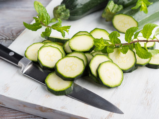 Cutting fresh zucchini on wooden board. Cooking vegetables