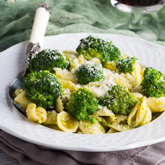 Orecchiette pasta with broccoli in white dish on wooden table. Easy recipe for lunch.