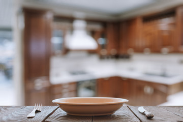 empty plate with fork and knife on wooden table