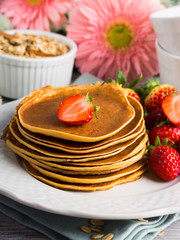Stack of oatmeal flour pancakes with strawberries on white dish