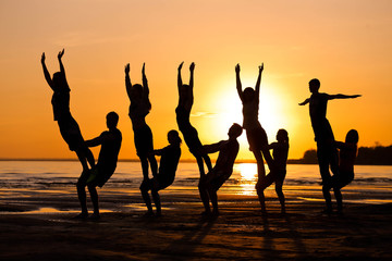 Silhouettes against the sunset are engaged in sports, fitness, yoga. A group of people.