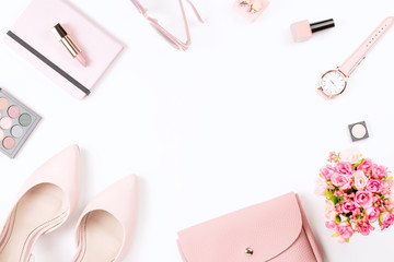 Fashion blogger workspace flat lay with pumps, cosmetics, purse, planner book and flowers.