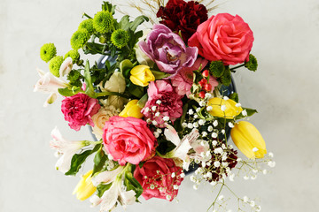 Top view of colorful bouquet of spring flowers - pink roses and yellow tulips, on a gray background