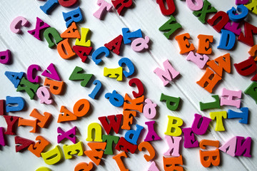 Multicolor letters on a white wooden background. Colorful wooden alphabet on a table.	