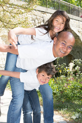 single Father Giving Children Piggyback Ride Outdoors ton son and daughter