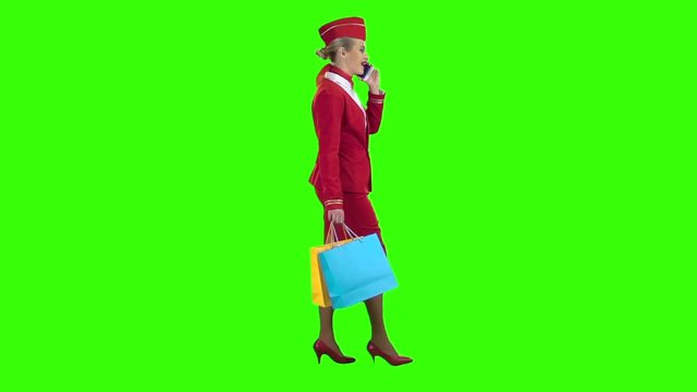 Girl comes with shopping bags talking on the phone. Green screen. Side view. Slow motion