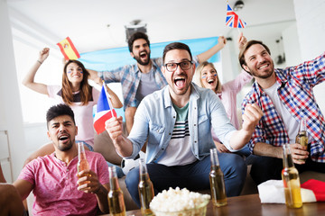 Soccer fans emotionally watching game in the living room.