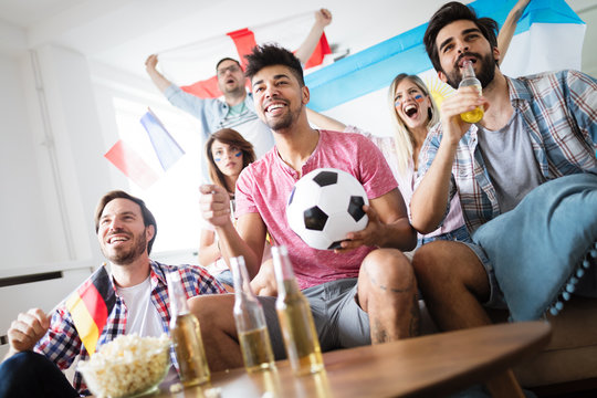 Soccer fans emotionally watching game in the living room.