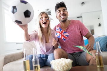 Young couple sport fans watching match on television