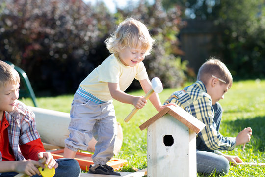 Children boys make a birdhouse for the birds in the garden of a summer sunny day