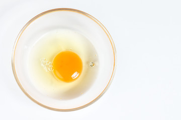 Raw Egg Yolk and white liquid in transparent glass bowl white background