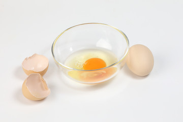Raw Egg Yolk and white liquid in transparent glass bowl eggshell white background