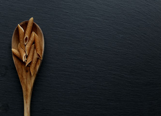 Whole macaroni on a ladle over slate board. To view