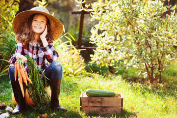 happy farmer child girl sitting with autumn harvest in the garden. Growing fresh organic...
