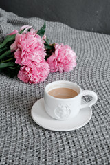 A cup of coffee and peonies on a gray background