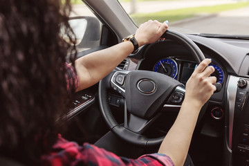 Naklejka premium Brunette lady is holding her hands behind wheel of car.